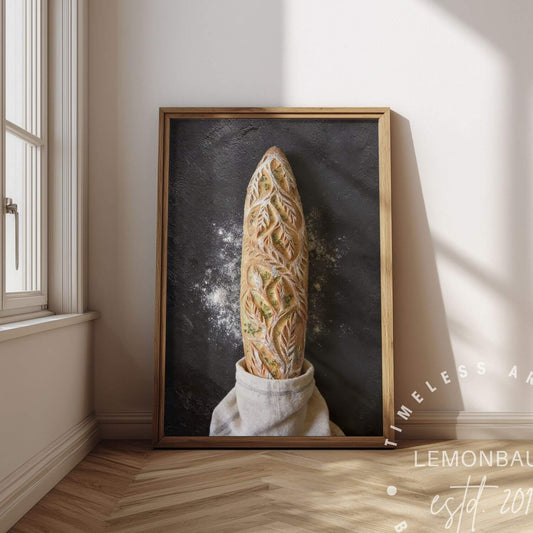 A framed vertical art print poster. The artwork shows a loaf of bread rising from a white cloth against a dark chalkboard-like background.