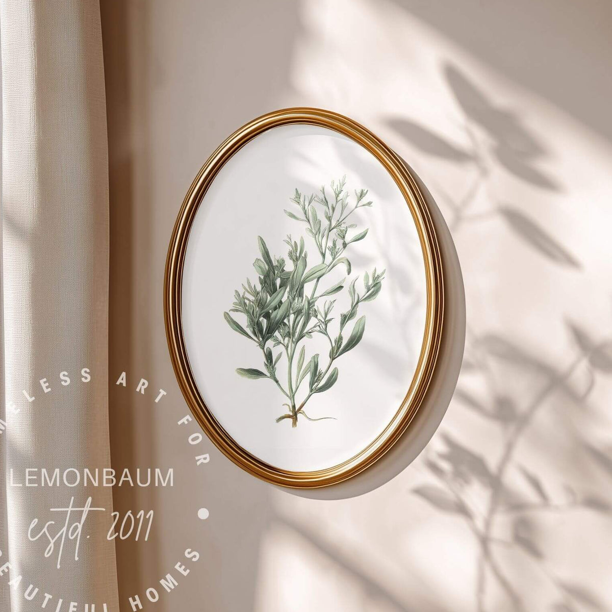Oval framed botanical art print featuring a green leafy plant illustration on a white background, with a gold frame hanging on a beige wall. Soft sunlight and leaf shadows fall across the wall, and a watermark reads 'Lemonbaum' with 'Timeless Art for Beautiful Homes'.